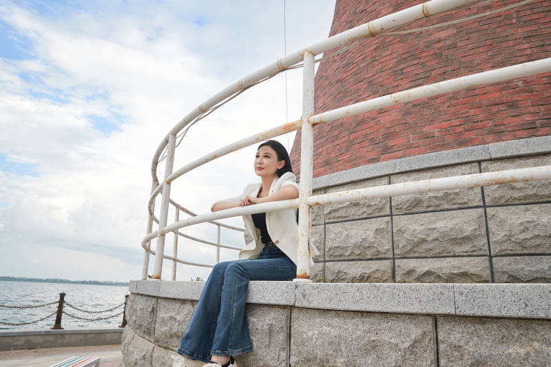 盛夏在景区湖边灯塔上拍照游玩的美女图片