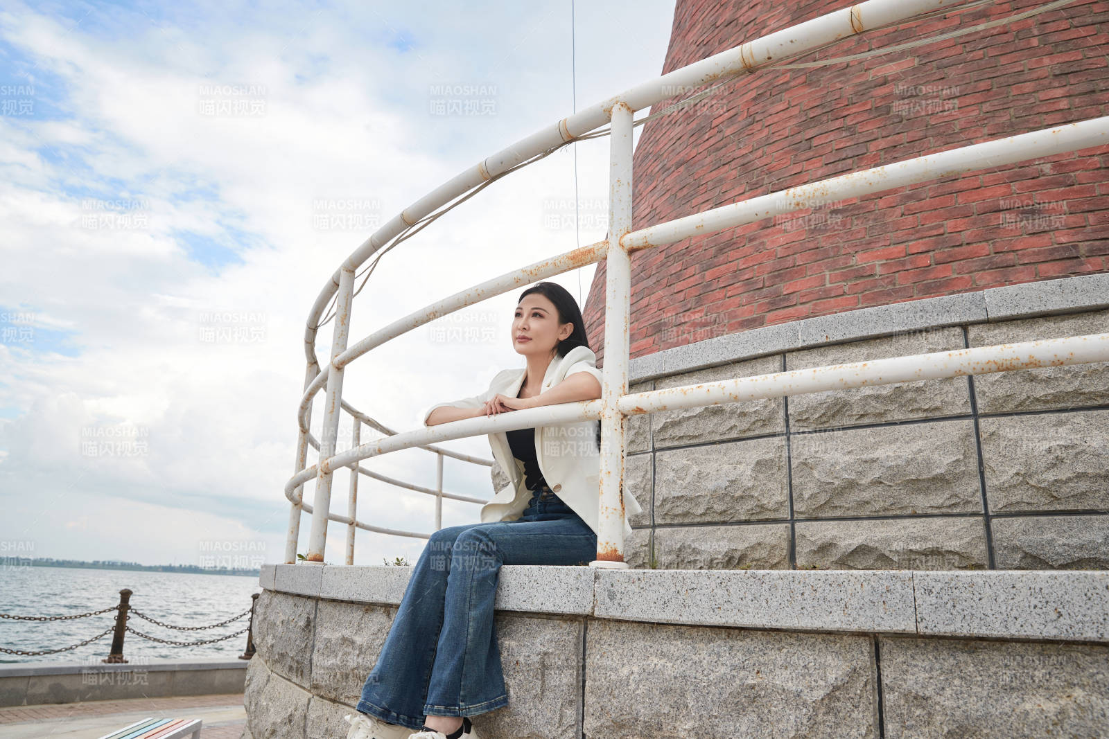 盛夏在景区湖边灯塔上拍照游玩的美女图片