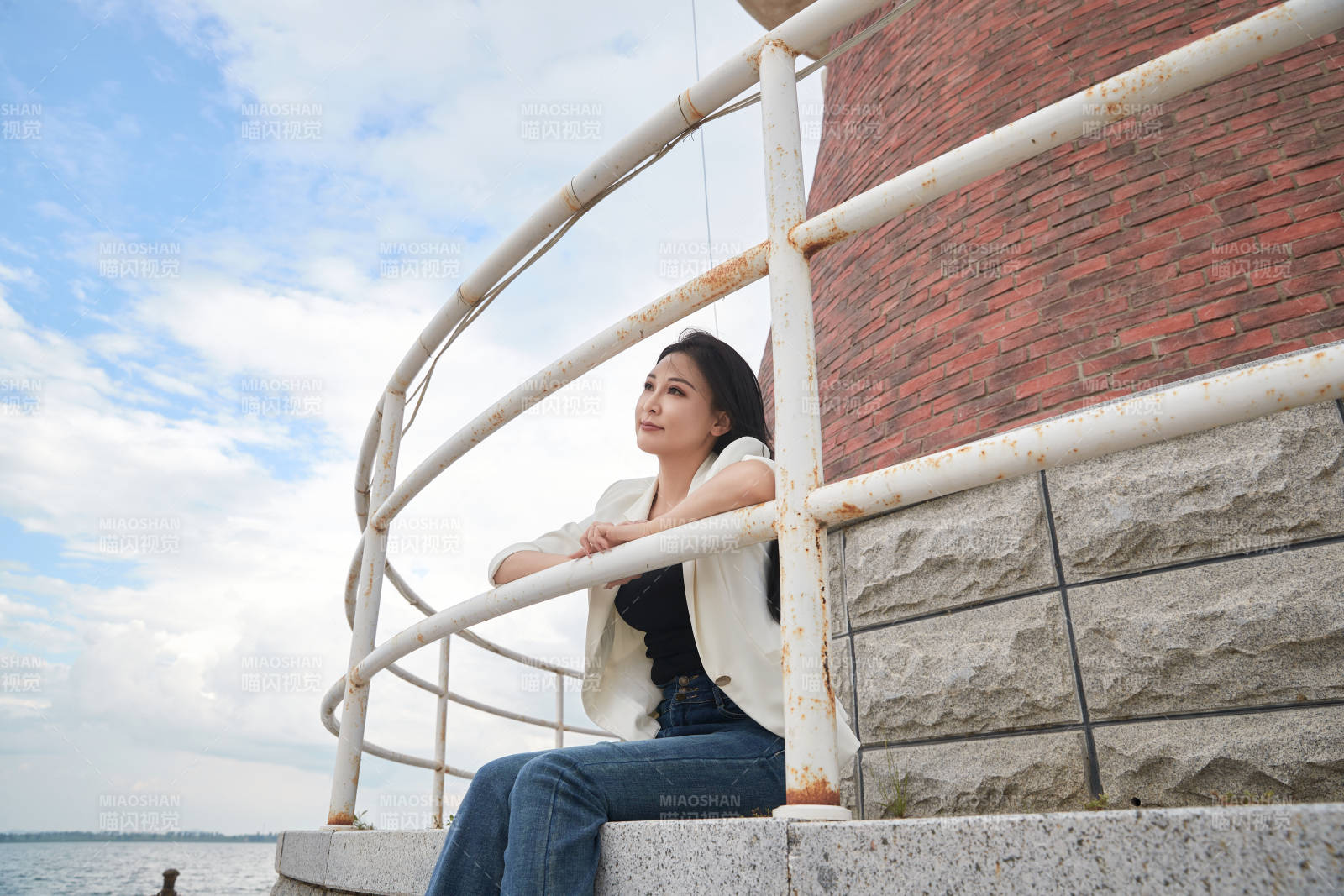 盛夏在景区湖边灯塔上拍照游玩的美女图片