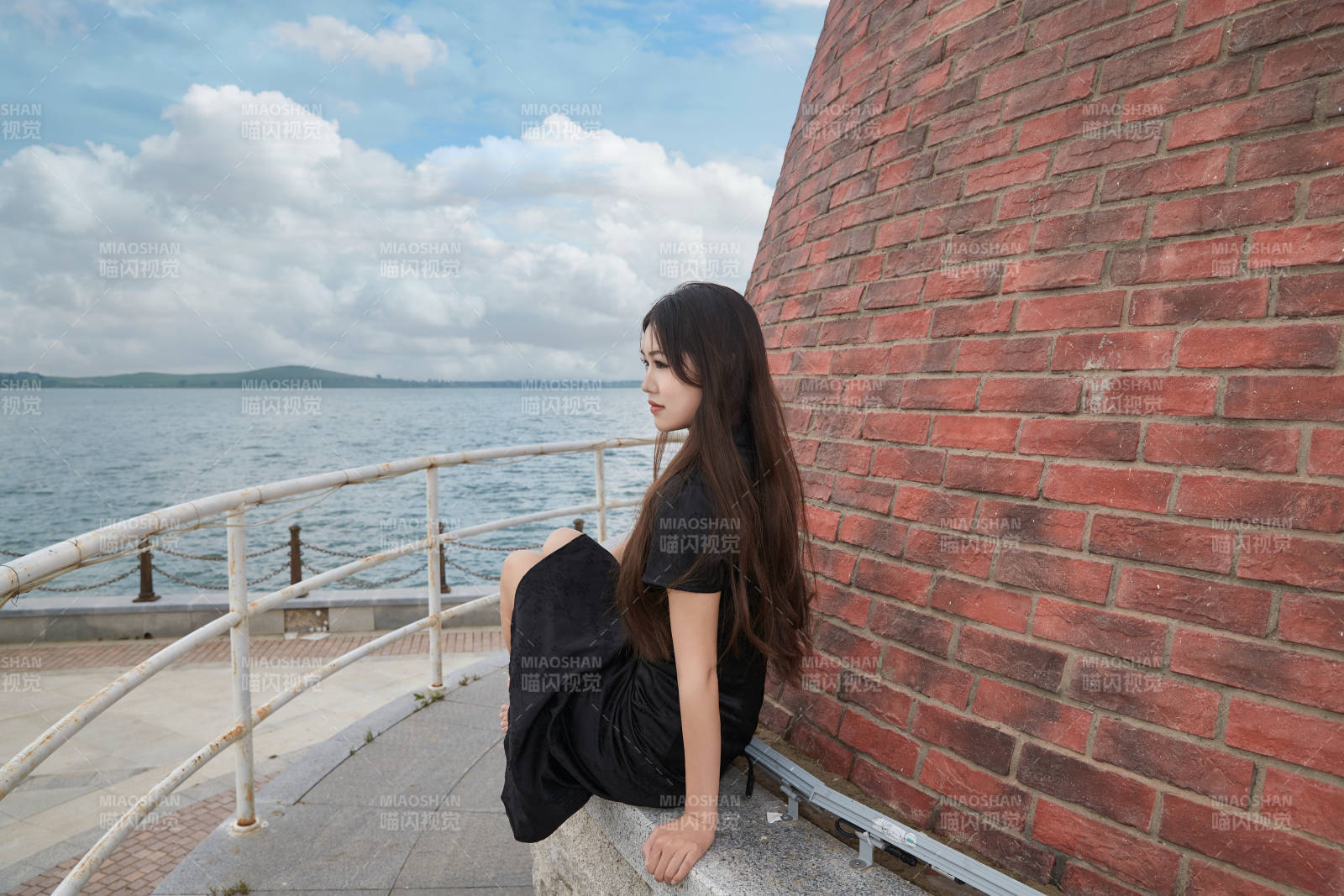 盛夏在景区湖边灯塔上拍照游玩的美女图片