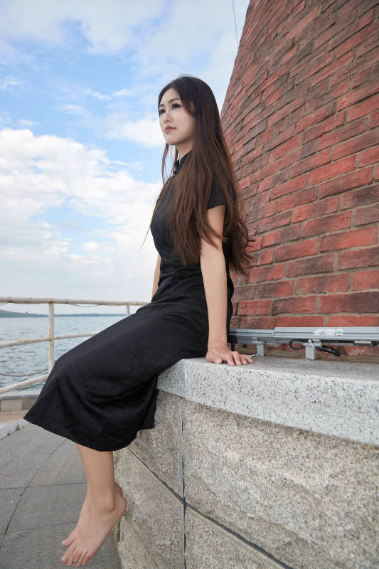 盛夏在景区湖边灯塔上拍照游玩的美女图片