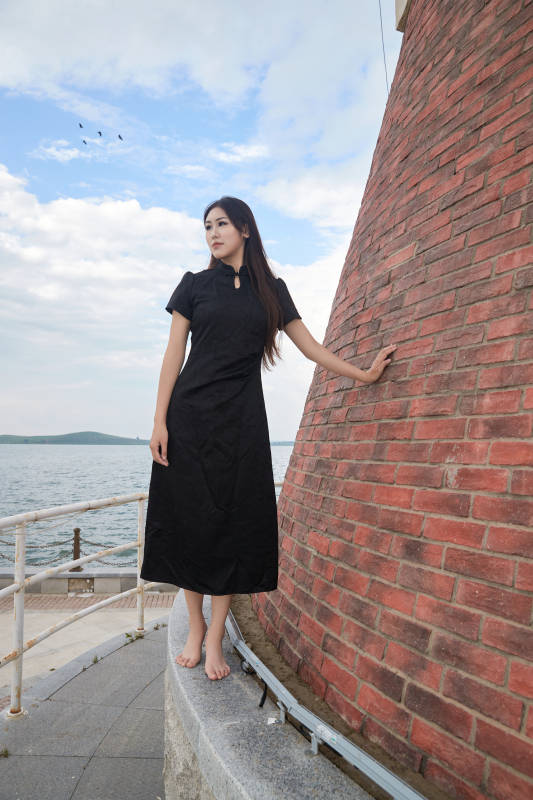 盛夏在景区湖边灯塔上拍照游玩的美女图片