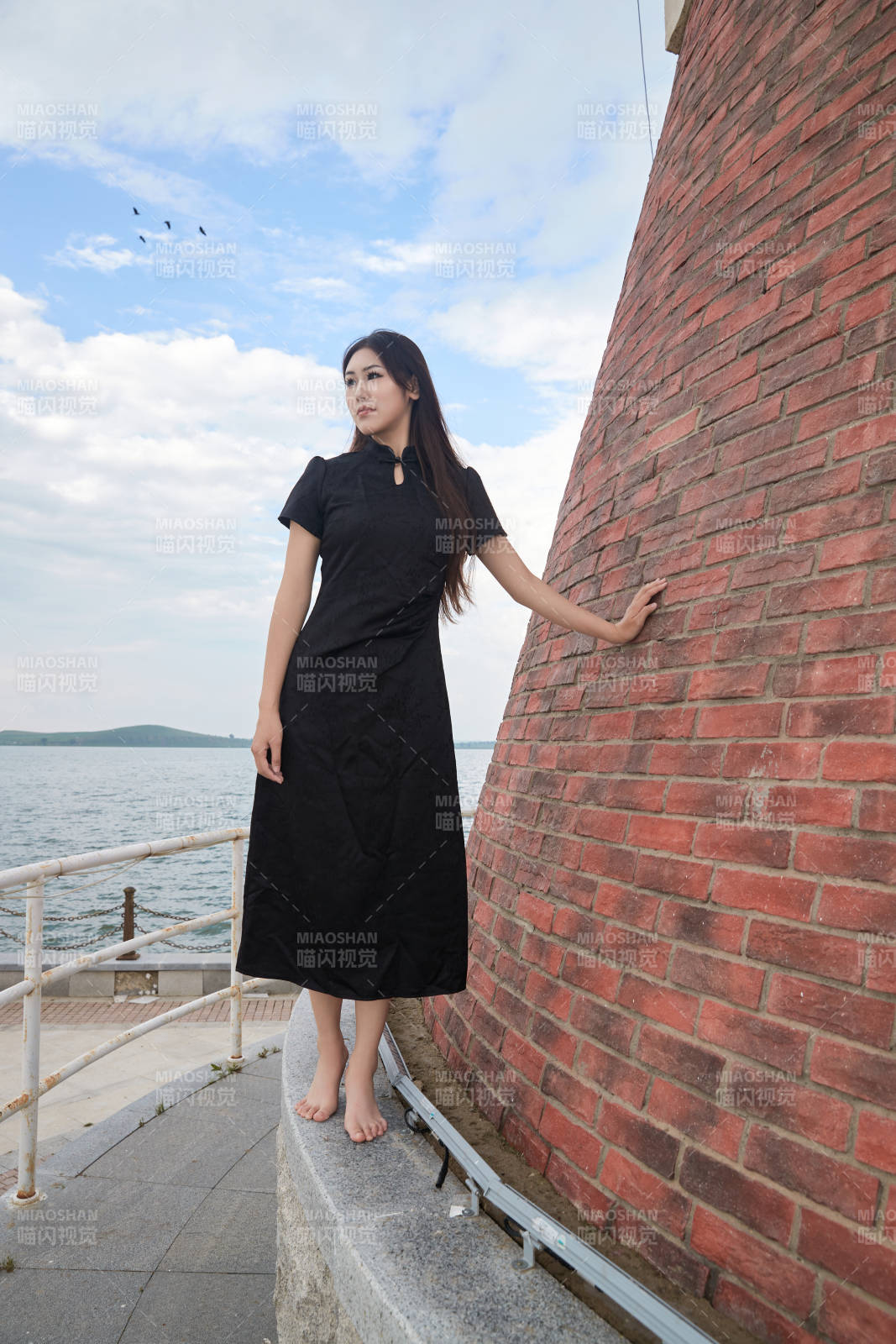 盛夏在景区湖边灯塔上拍照游玩的美女图片