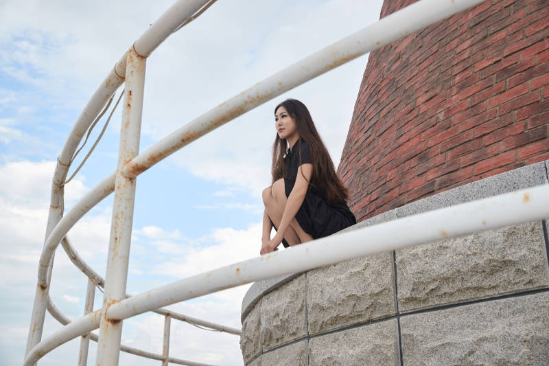 盛夏在景区湖边灯塔上拍照游玩的美女图片