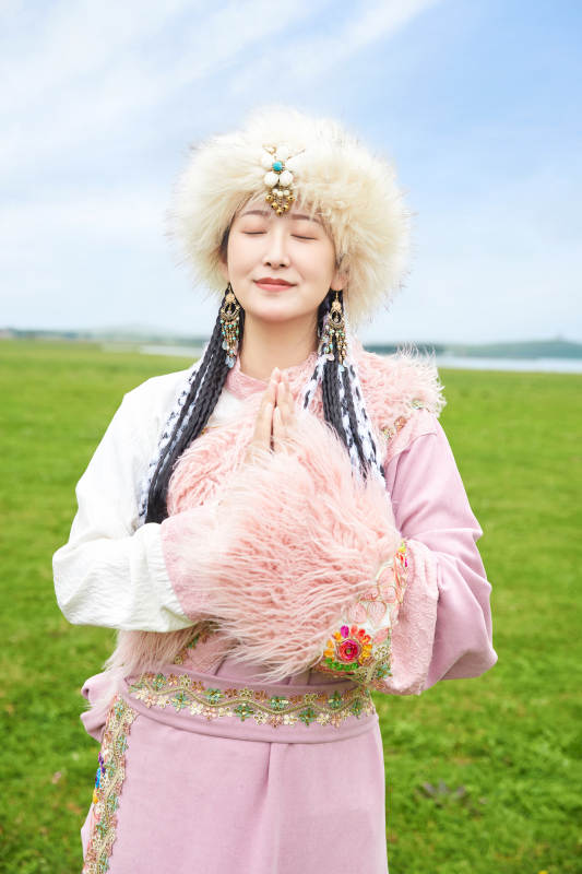 身穿藏族服饰在草原景区拍照的美女图片