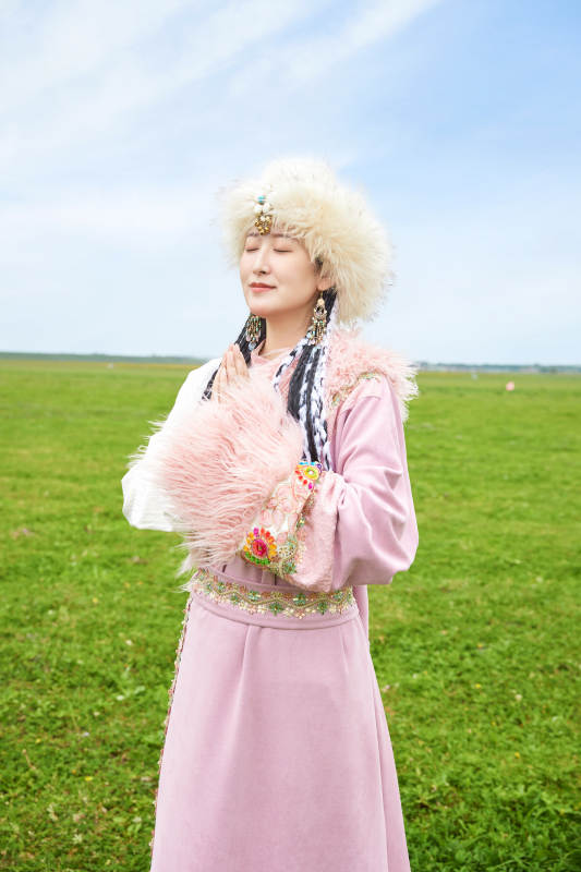 身穿藏族服饰在草原景区拍照的美女图片
