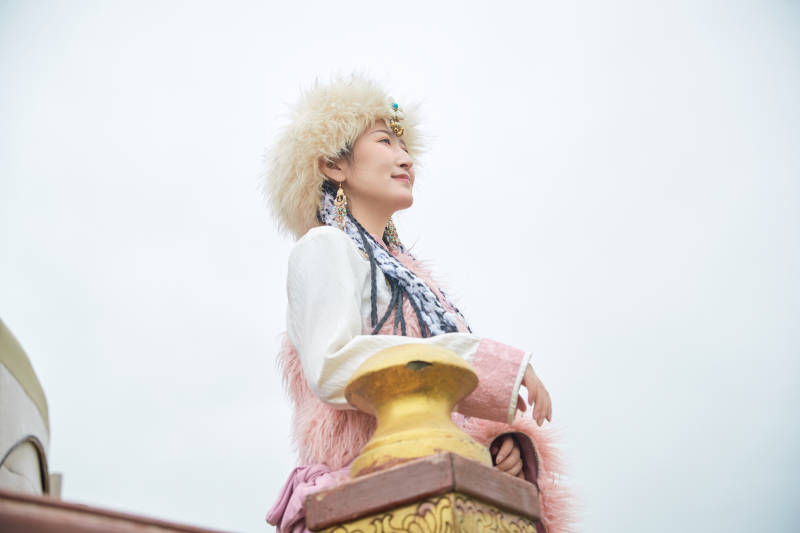 身穿藏族服饰在草原景区拍照的美女图片