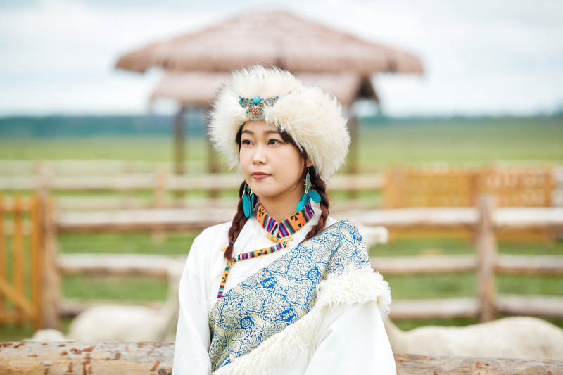 穿藏族服饰的姑娘在羊驼饲养基地拍照图片