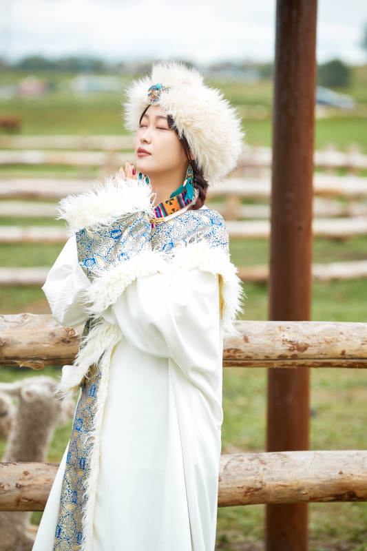 穿藏族服饰的姑娘在羊驼饲养基地拍照图片