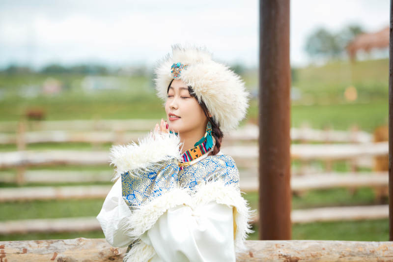 穿藏族服饰的姑娘在羊驼饲养基地拍照图片
