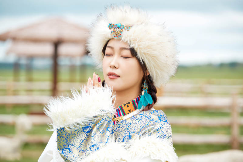 穿藏族服饰的姑娘在羊驼饲养基地拍照图片