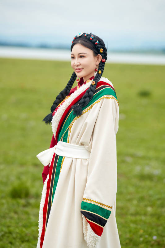 身穿红色藏族服饰在草原景区拍照的美女图片