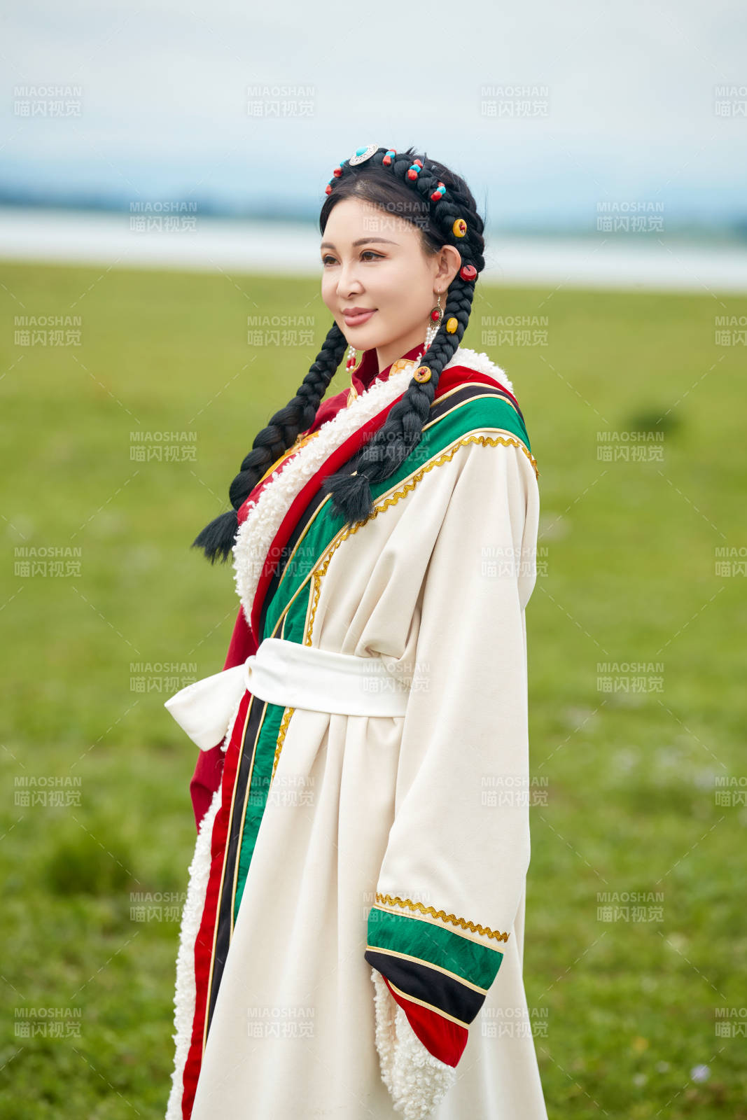 身穿红色藏族服饰在草原景区拍照的美女图片