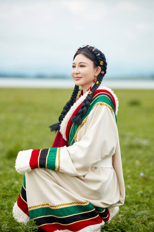 身穿红色藏族服饰在草原景区拍照的美女图片
