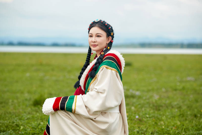 身穿红色藏族服饰在草原景区拍照的美女图片