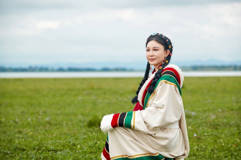 身穿红色藏族服饰在草原景区拍照的美女图片