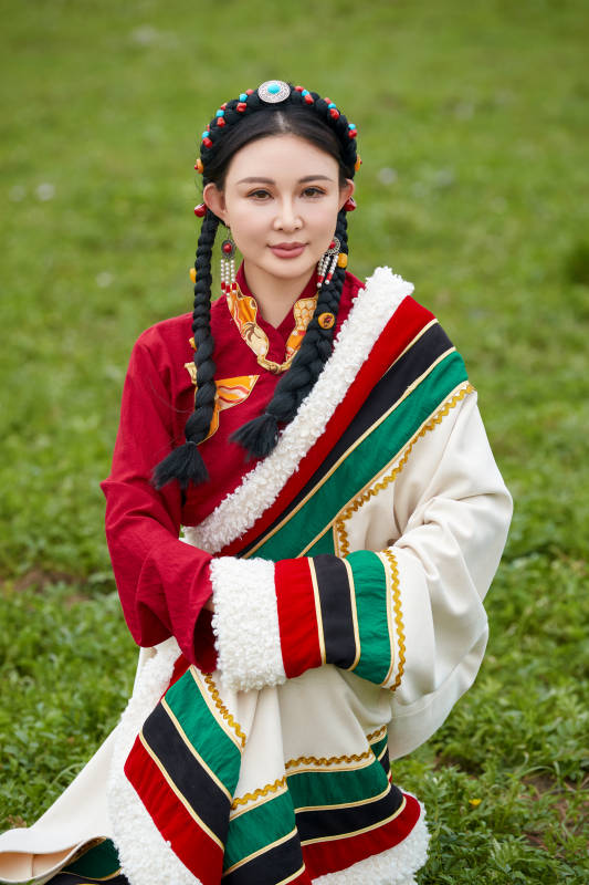 身穿红色藏族服饰在草原景区拍照的美女图片