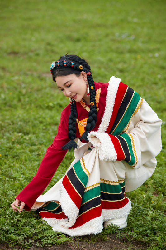 身穿红色藏族服饰在草原景区拍照的美女图片