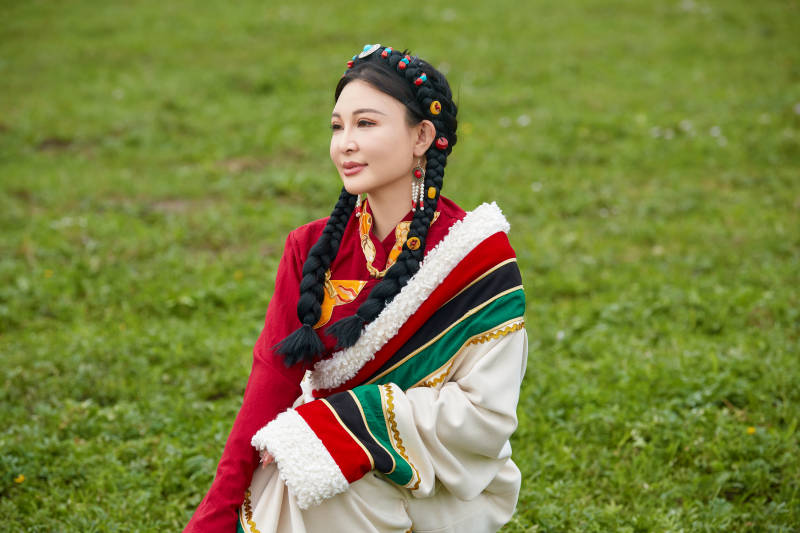 身穿红色藏族服饰在草原景区拍照的美女图片