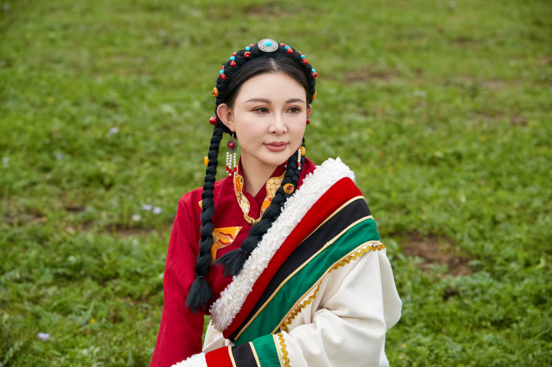 身穿红色藏族服饰在草原景区拍照的美女图片