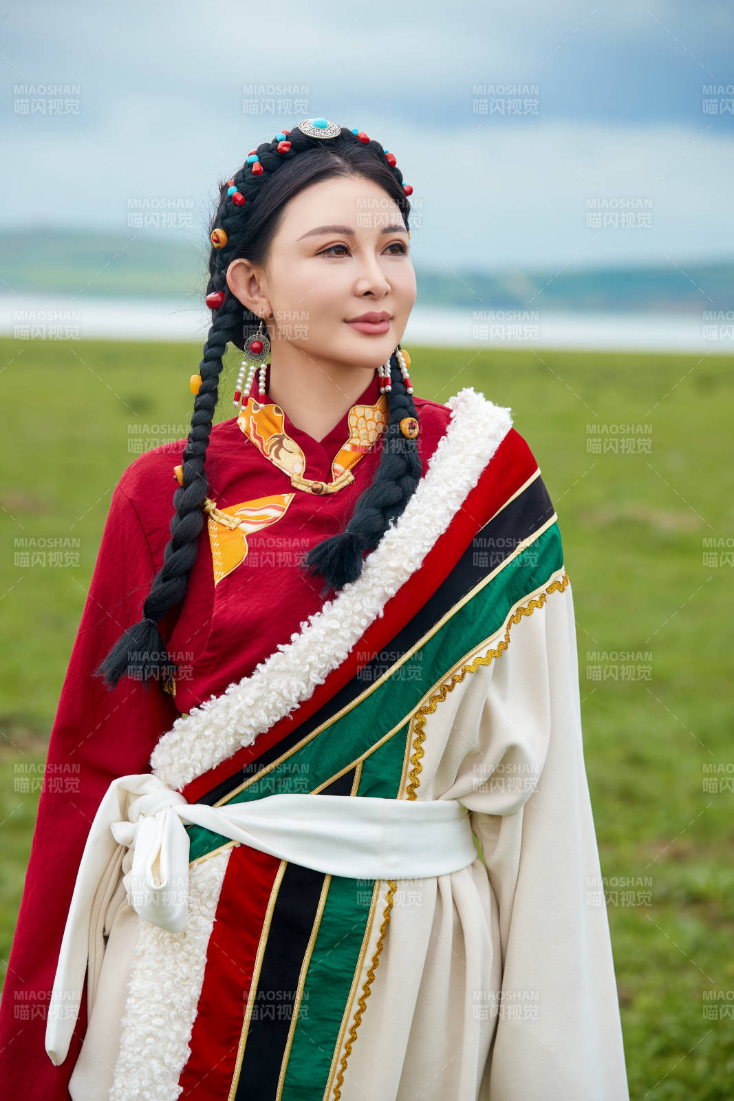 身穿红色藏族服饰在草原景区拍照的美女图片