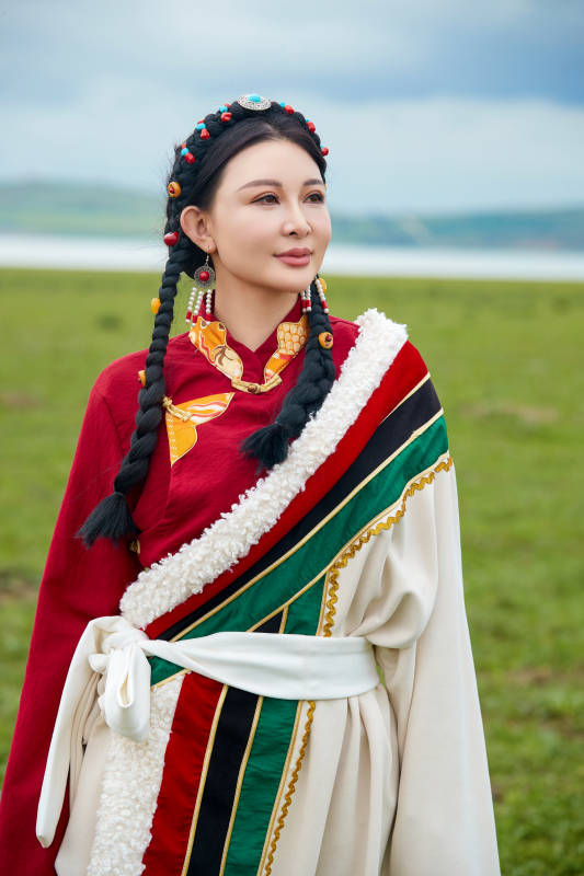 身穿红色藏族服饰在草原景区拍照的美女图片