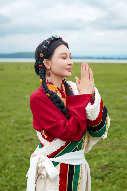 身穿红色藏族服饰在草原景区拍照的美女图片