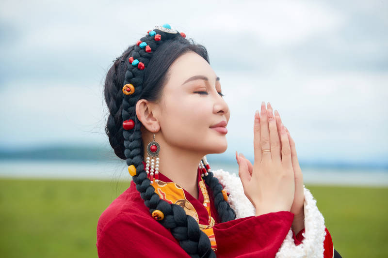身穿红色藏族服饰在草原景区拍照的美女图片