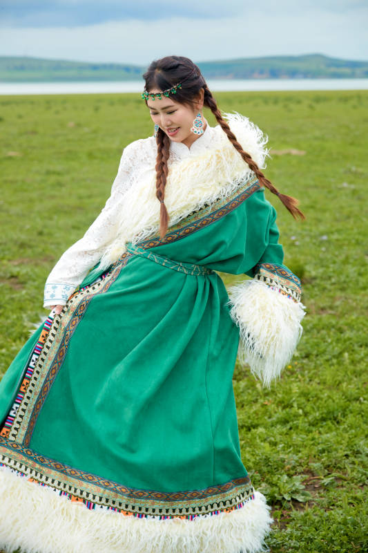 身穿绿色藏族服饰在草原跳舞的美女图片