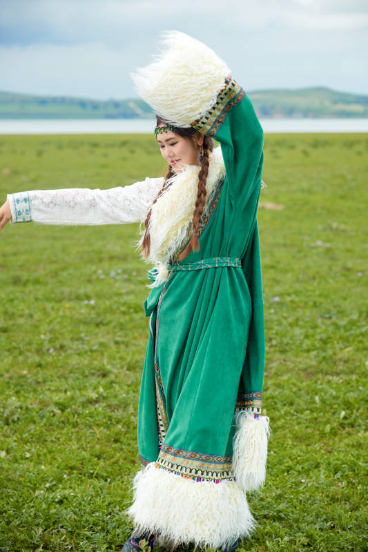 身穿绿色藏族服饰在草原跳舞的美女图片