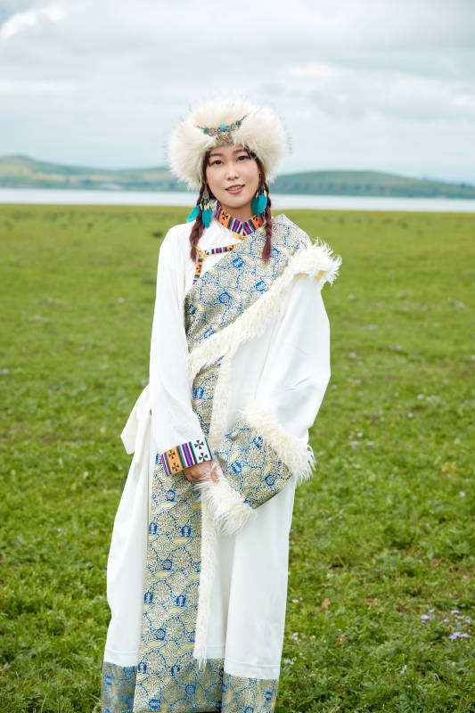 穿白色藏族服饰在草原拍照的少女图片