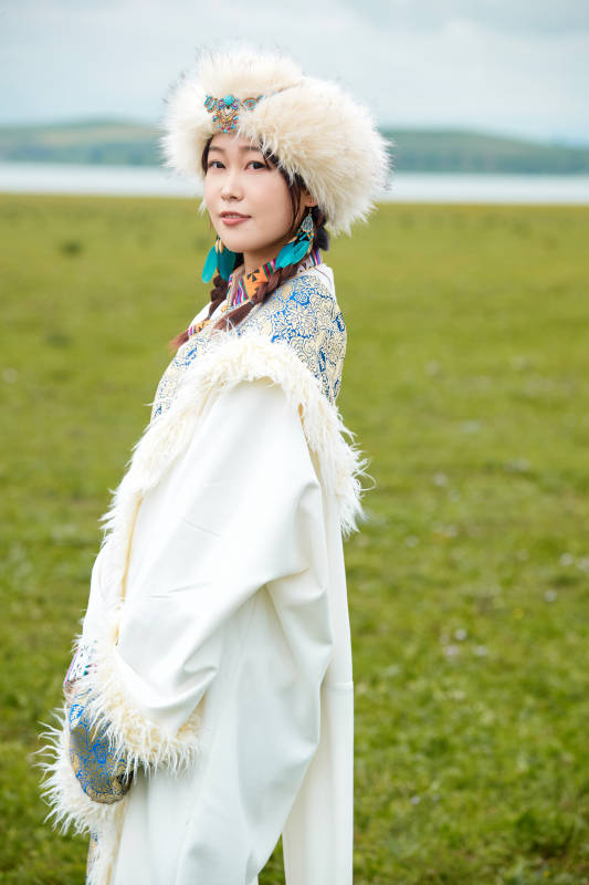 穿白色藏族服饰在草原拍照的少女图片