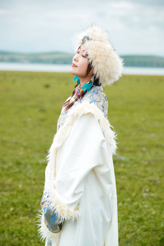 穿白色藏族服饰在草原拍照的少女图片