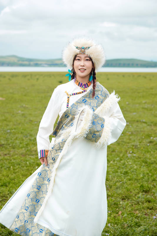 穿白色藏族服饰在草原拍照的少女图片