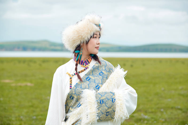 穿白色藏族服饰在草原拍照的少女图片