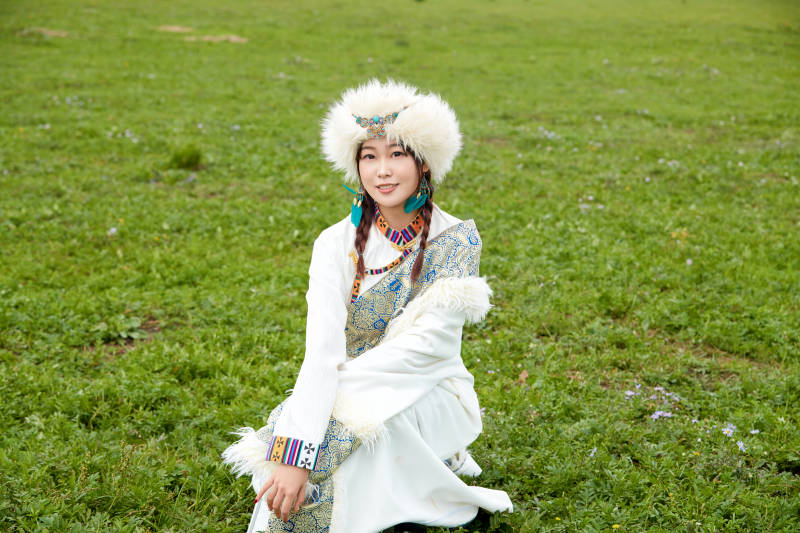穿白色藏族服饰在草原拍照的少女图片