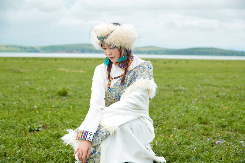 穿白色藏族服饰在草原拍照的少女图片