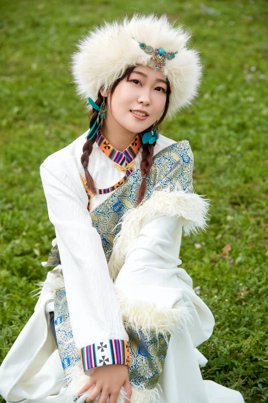穿白色藏族服饰在草原拍照的少女图片