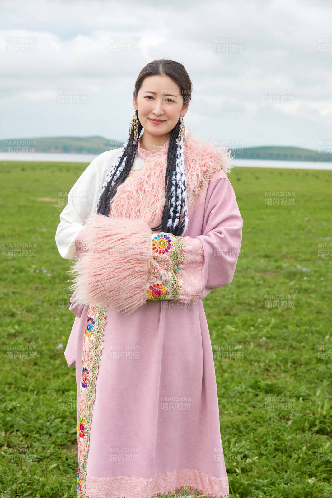 身穿粉色藏族服饰在草原拍照的少女图片