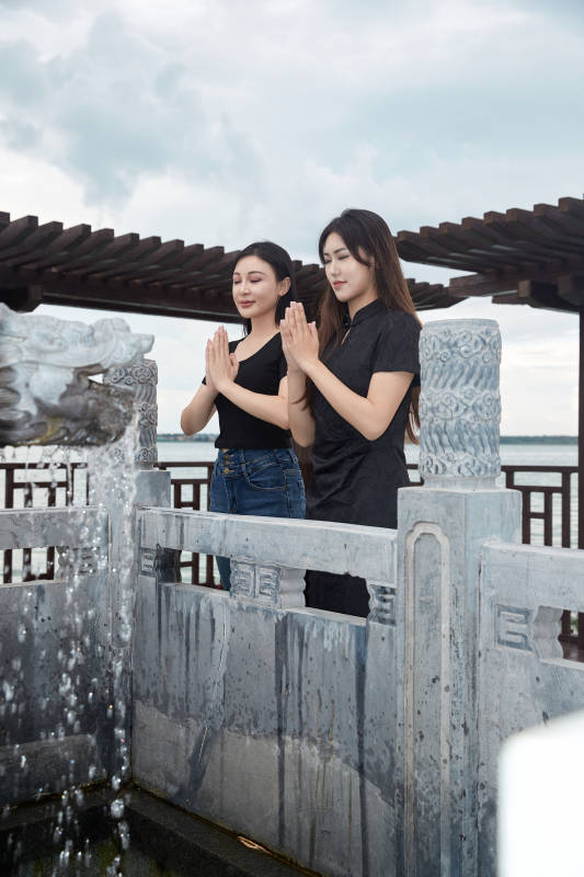 盛夏在景区湖边许愿井祈福的美女图片