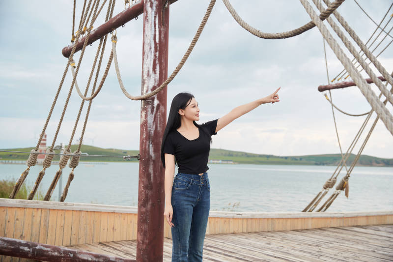 在湖畔木制帆船上拍照游玩的亚洲女性图片