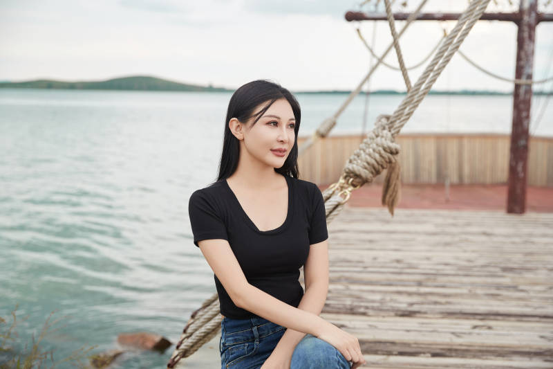 在湖畔木制帆船上拍照游玩的亚洲女性图片