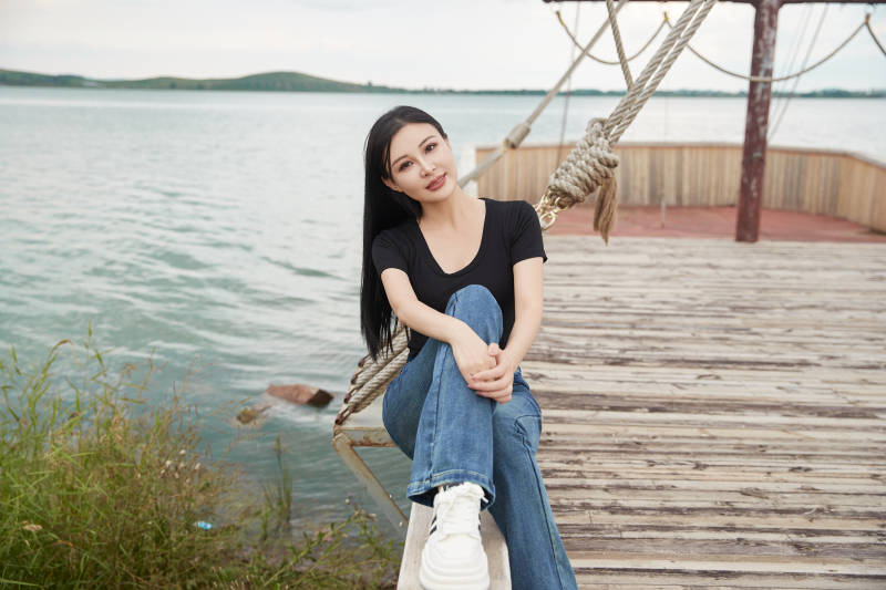 在湖畔木制帆船上拍照游玩的亚洲女性图片