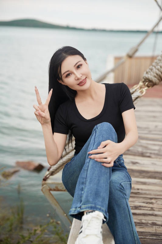 在湖畔木制帆船上拍照游玩的亚洲女性图片