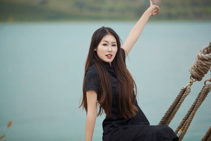 在湖畔木制帆船上拍照游玩的亚洲女性图片