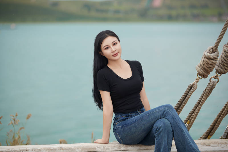 在湖畔木制帆船上拍照游玩的亚洲女性图片