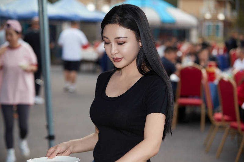 在户外烤全羊自助餐会品尝美食的美女图片