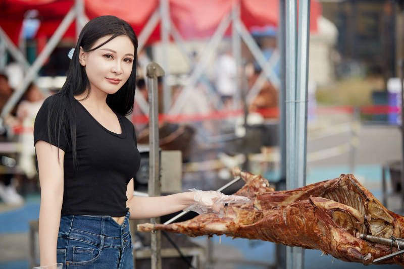 在户外烤全羊自助餐会品尝美食的美女图片