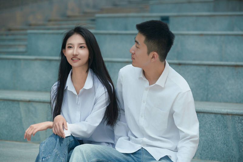 坐在户外台阶上的青年情侣图片