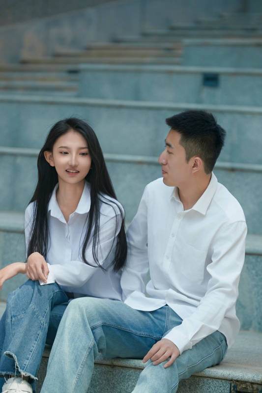 坐在户外台阶上的青年情侣图片